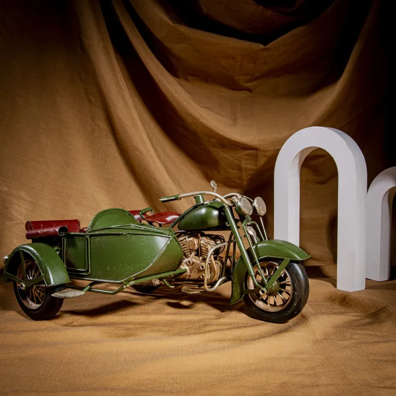 Olive green sidecar motorcycle decor piece styled against a draped backdrop