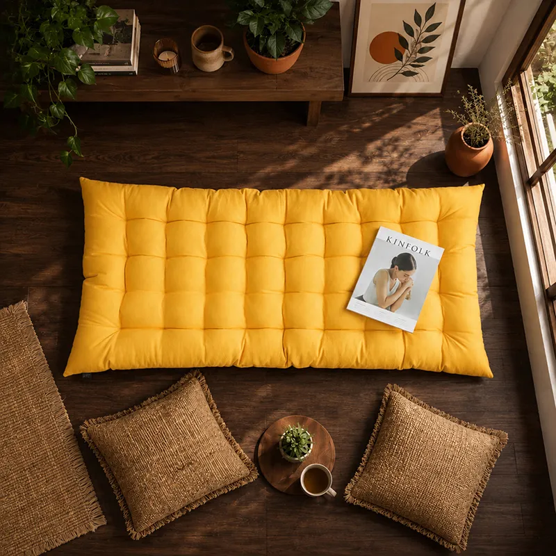 Mustard yellow rectangular floor cushion styled on a wooden floor