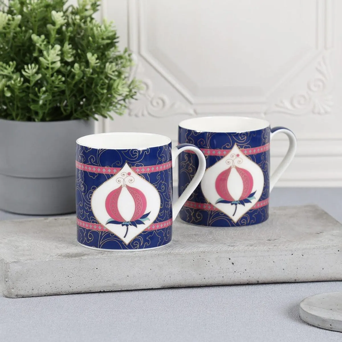 Pair of blue decorative coffee mugs with white interiors and curved handles