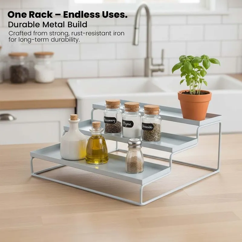 White metal tiered organiser styled on a kitchen counter with spice jars and plant