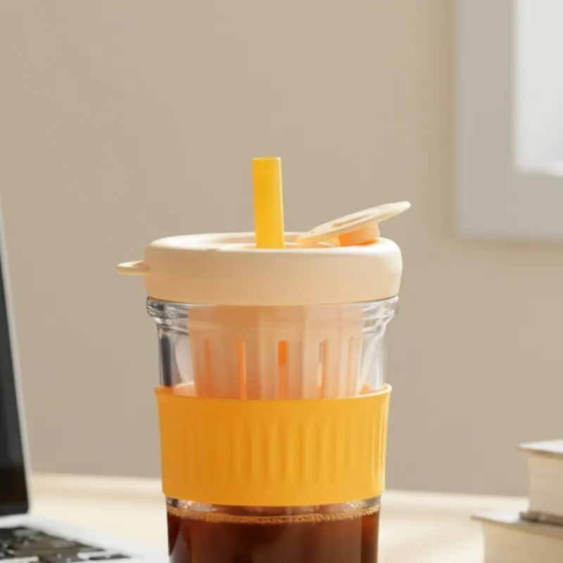 Close-up of glass tumbler with orange grip and cream lid