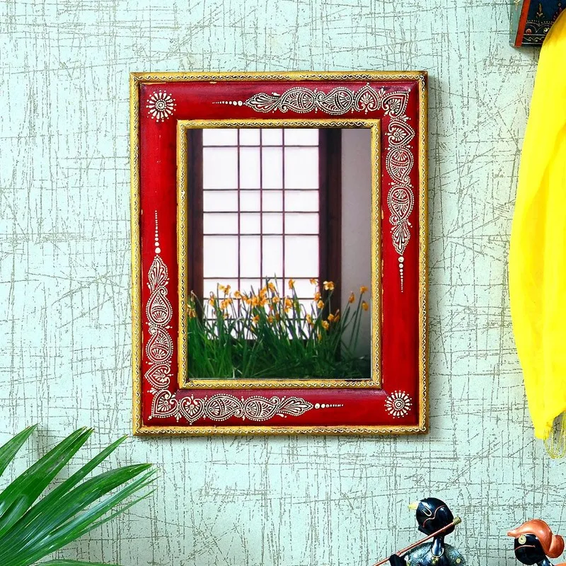 Red ornate wall mirror displayed against a patterned wall