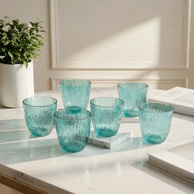 Six blue tinted textured drinking glasses arranged on a marble table