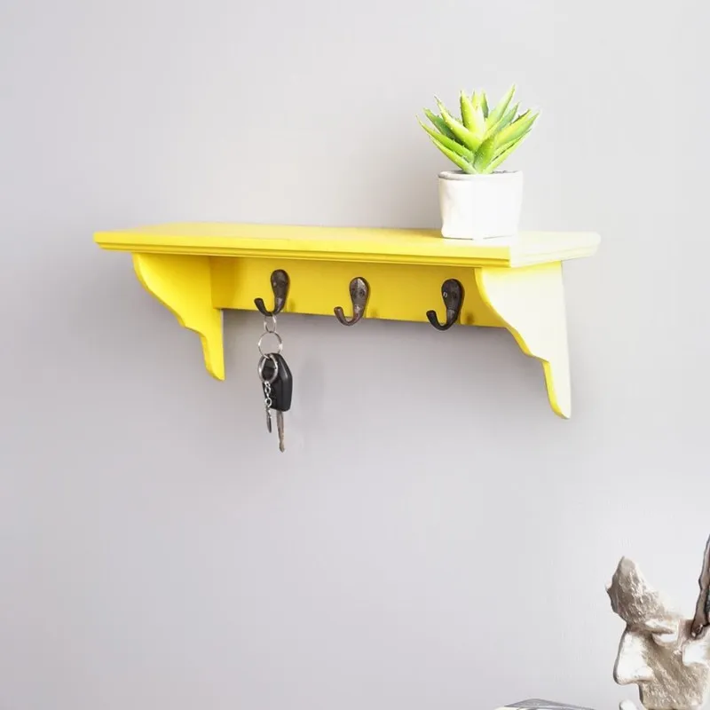 Angled view of yellow wooden key holder shelf with curved brackets
