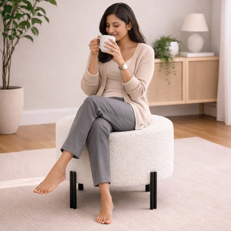 Woman seated on an off-white round ottoman with black legs