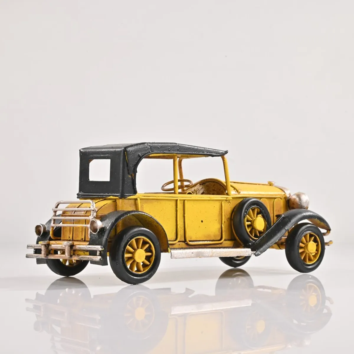 Side view of the yellow vintage model car showpiece on a white background