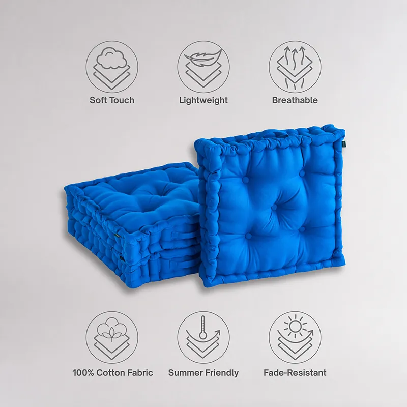 Stacked and upright classic blue square floor cushions on a plain backdrop