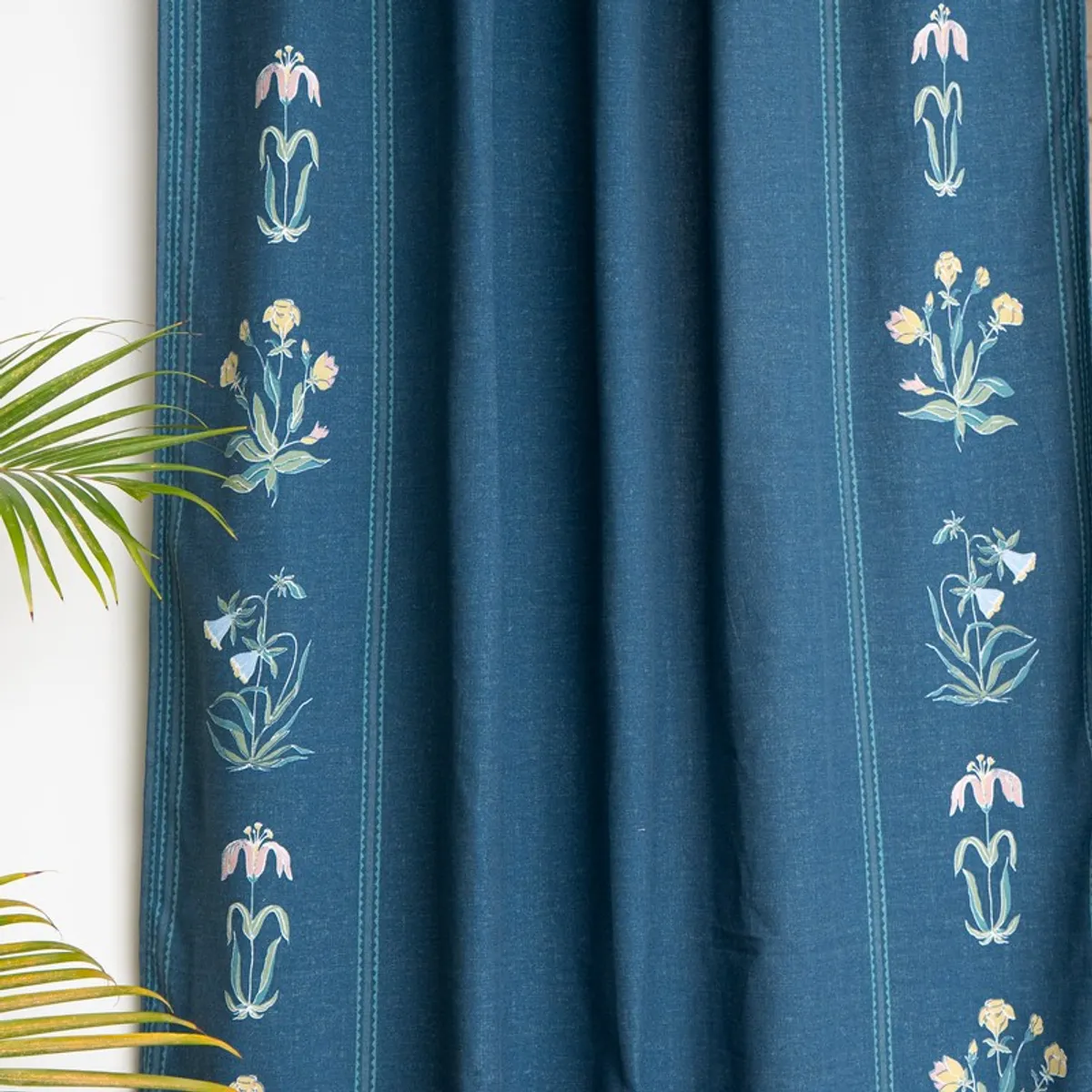 Close view of blue curtains with floral motifs arranged in vertical border panels