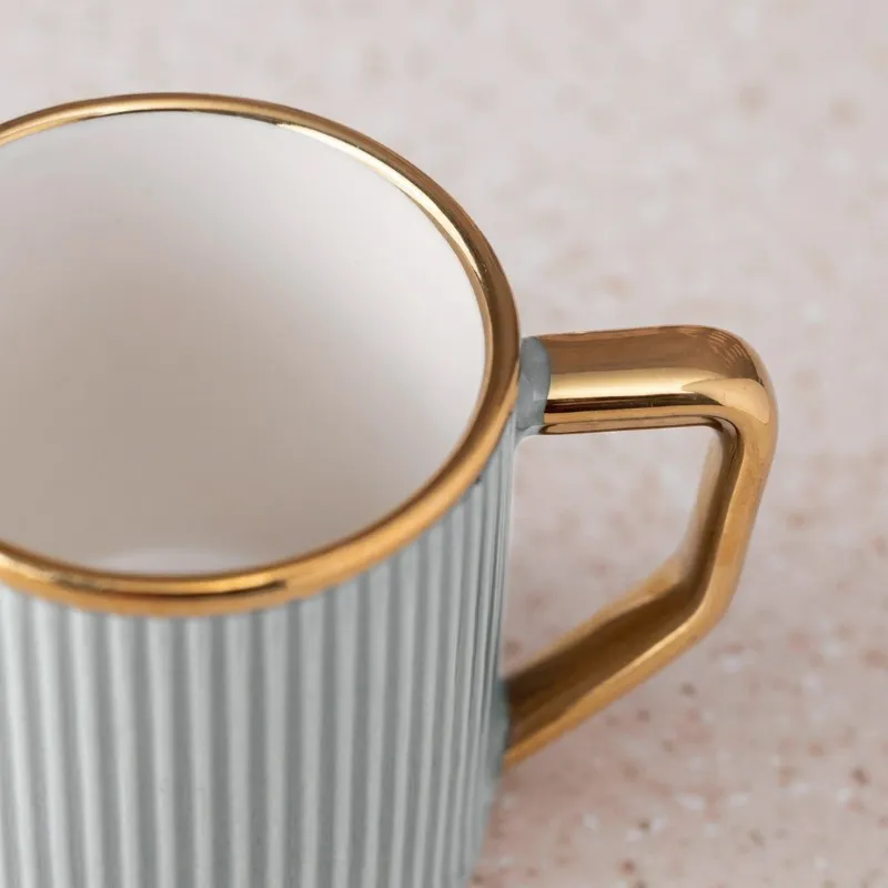 Close-up of a grey ribbed mug with a gold-toned rim and angular handle