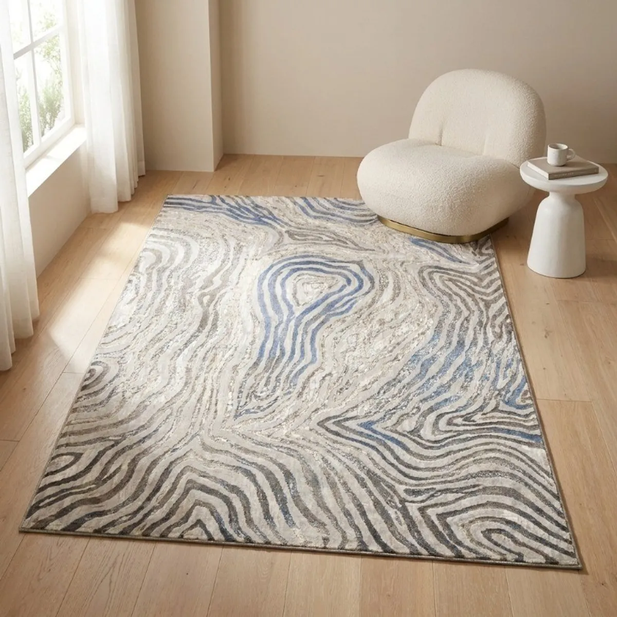 Rectangular abstract carpet in off white and blue styled beside a curved chair