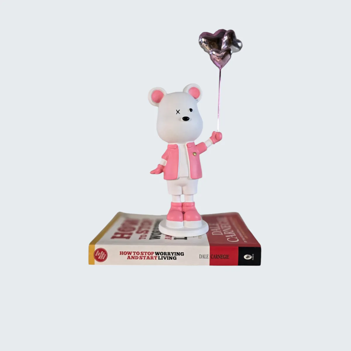 Pink and white bear showpiece displayed on top of books