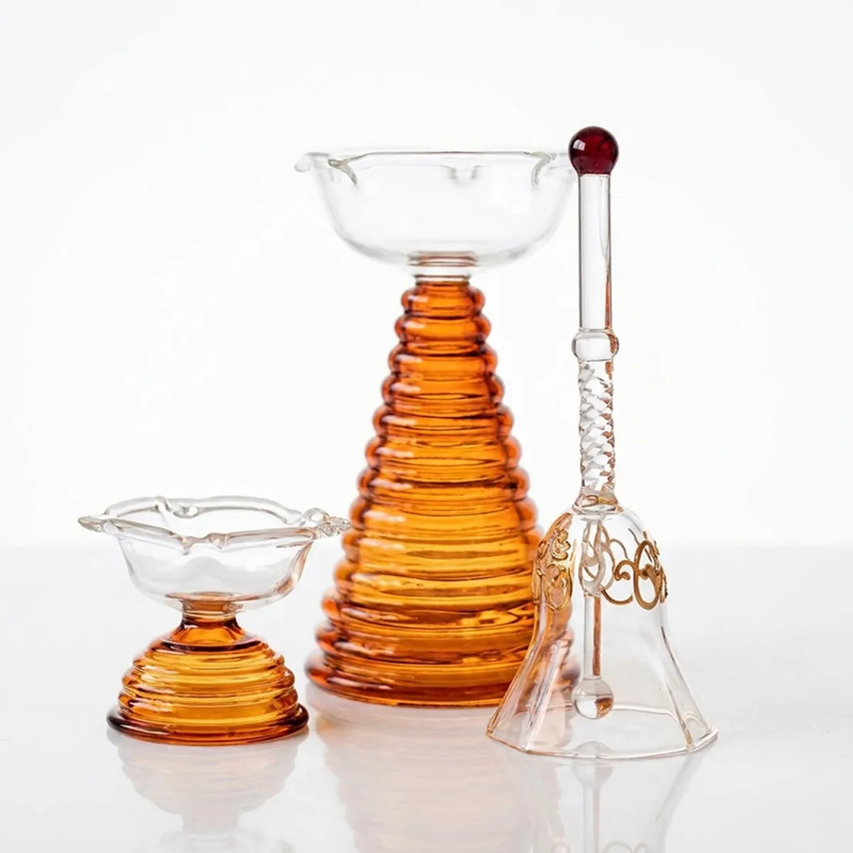 Brown and transparent glass pooja set arranged against a white background