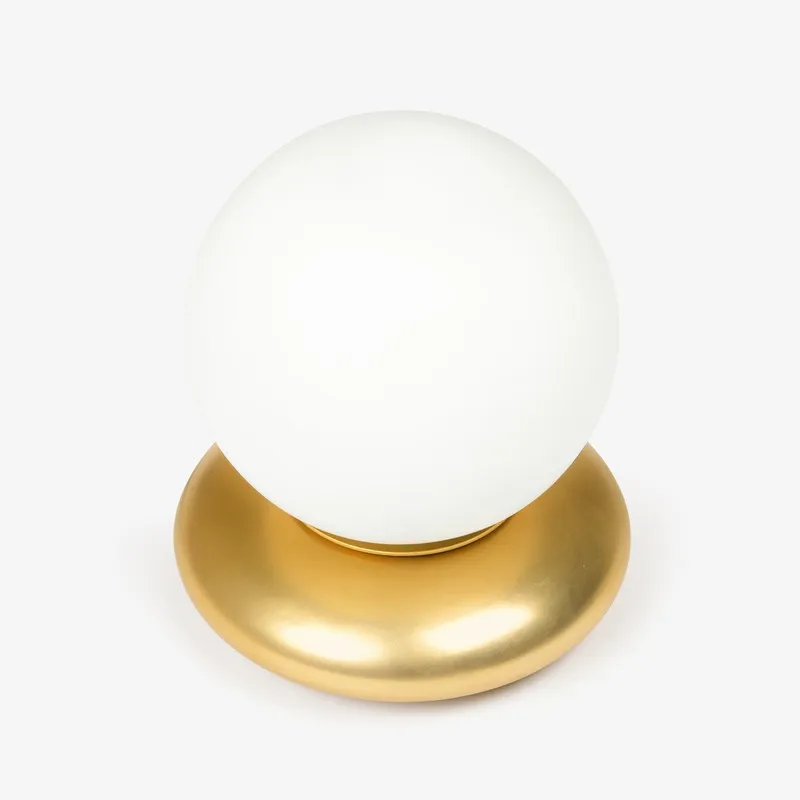 Front view of white globe table lamp on a gold base