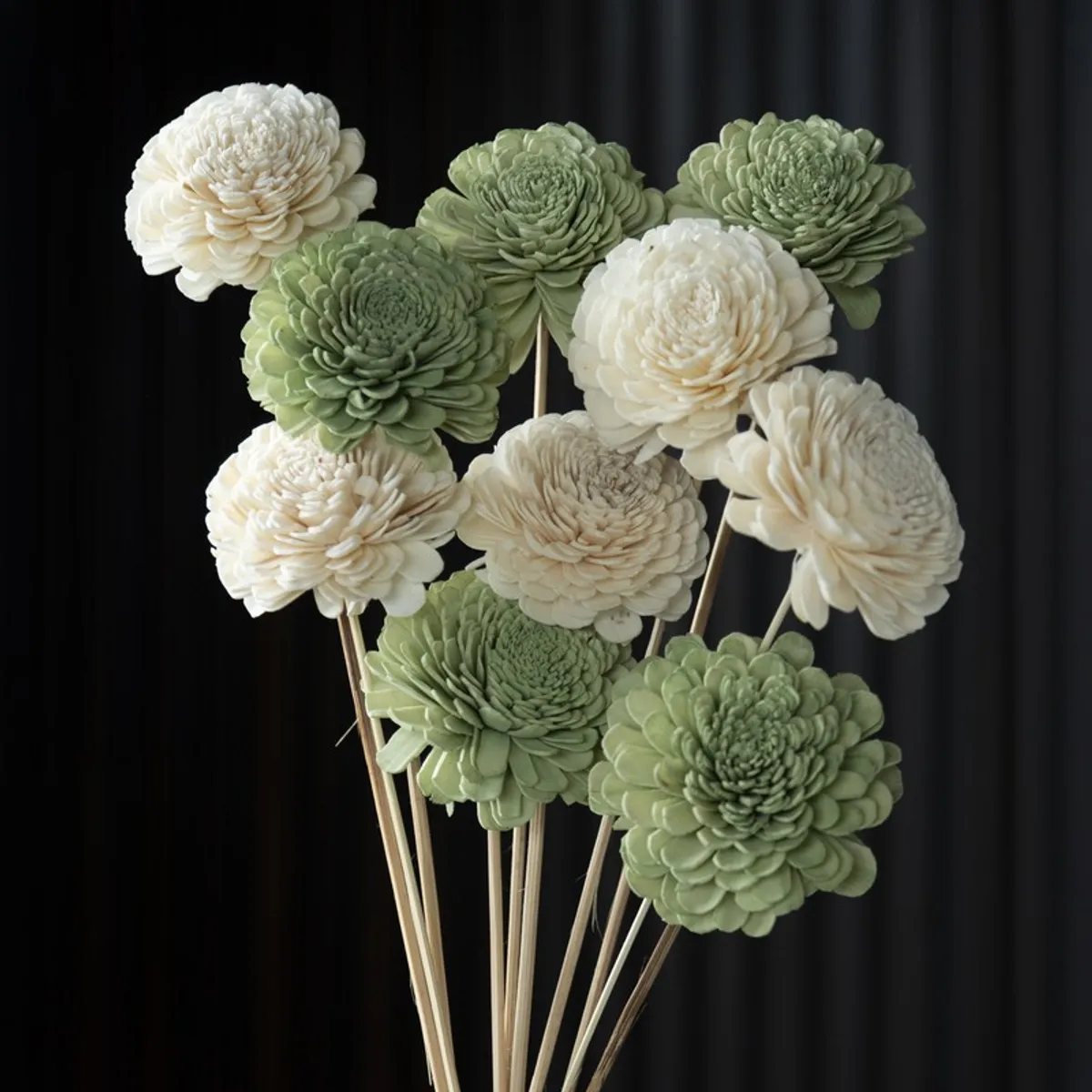Close-up of layered green and off-white pom-pom flower heads on slender sticks