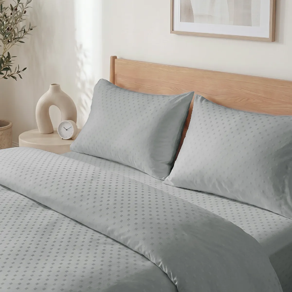 Close view of grey geometric dot duvet cover draped across pillows and bed