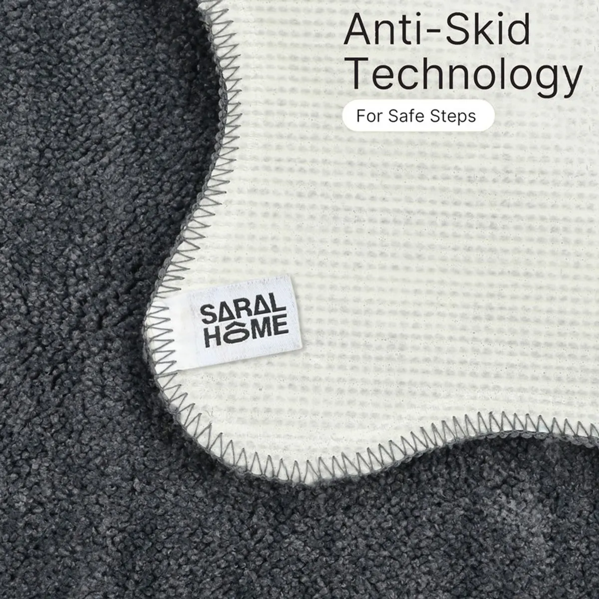 Close-up of the white anti-skid backing and stitched edge of a grey bath mat