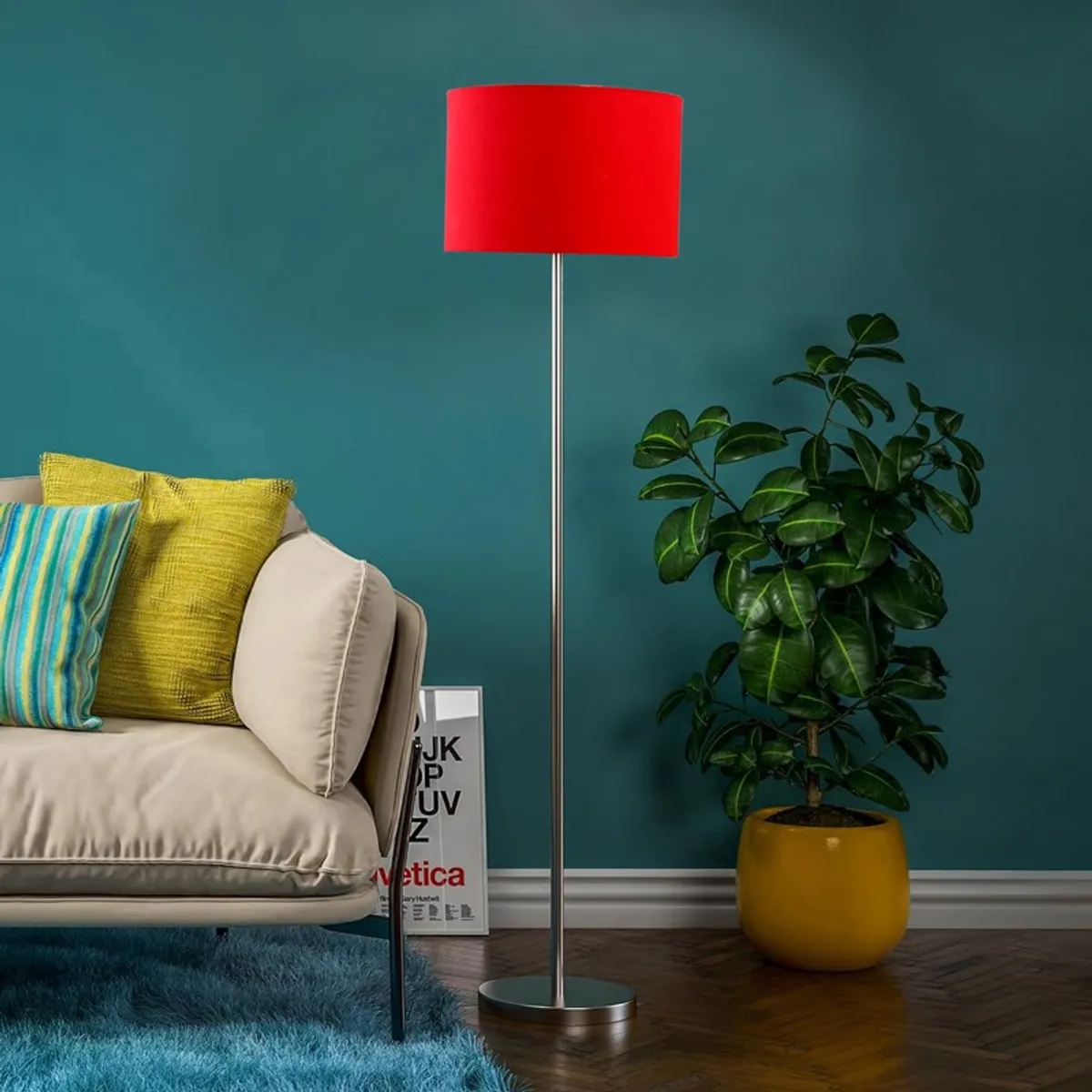 Red shade floor lamp beside a sofa and potted plant against a teal wall