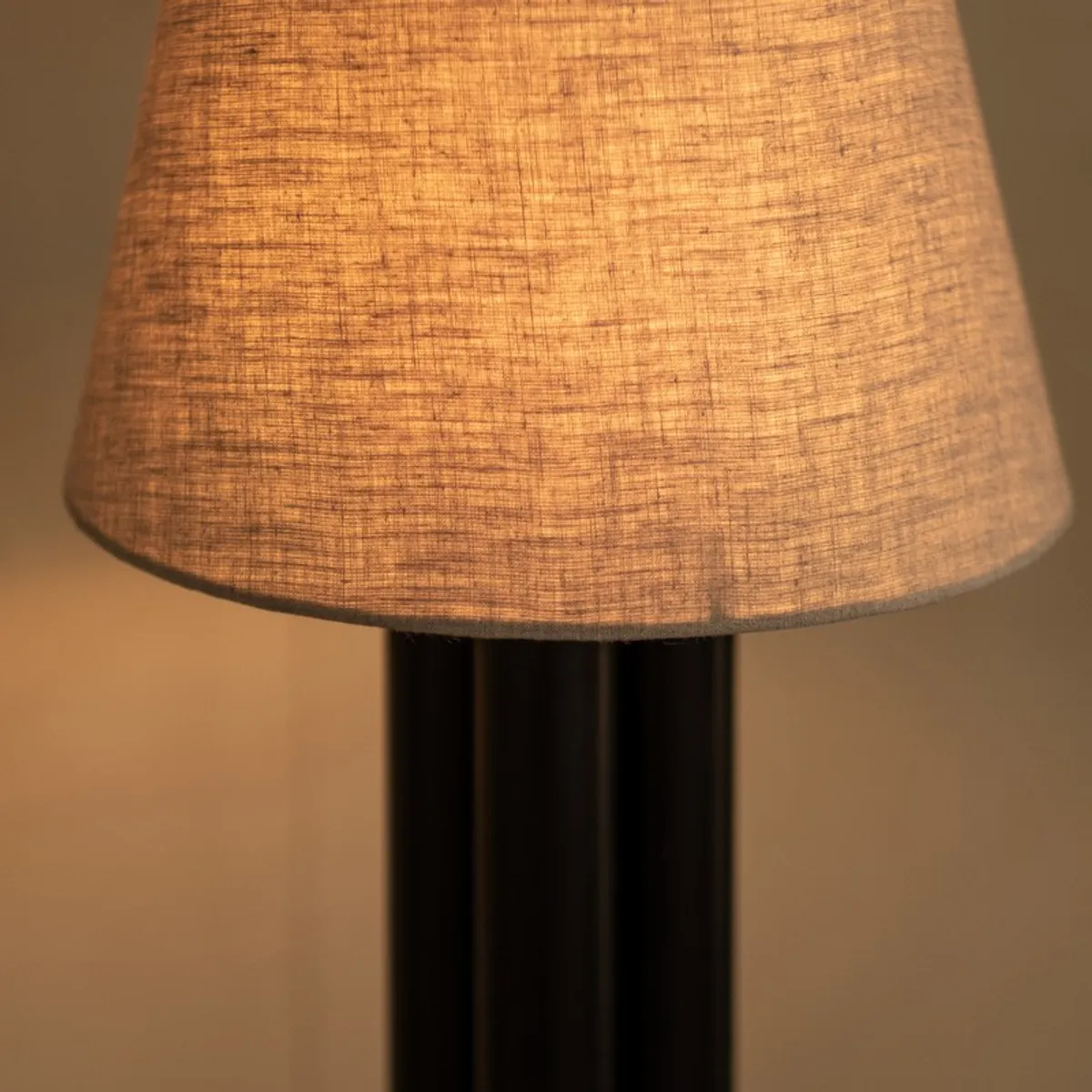 Close-up of the illuminated linen shade on the black lamp base