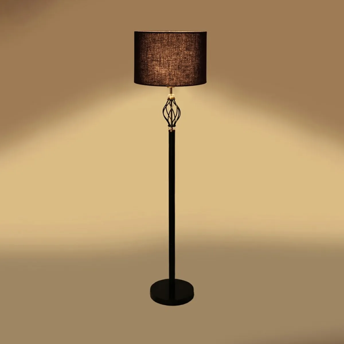 Black floor lamp with lit shade against a soft golden background
