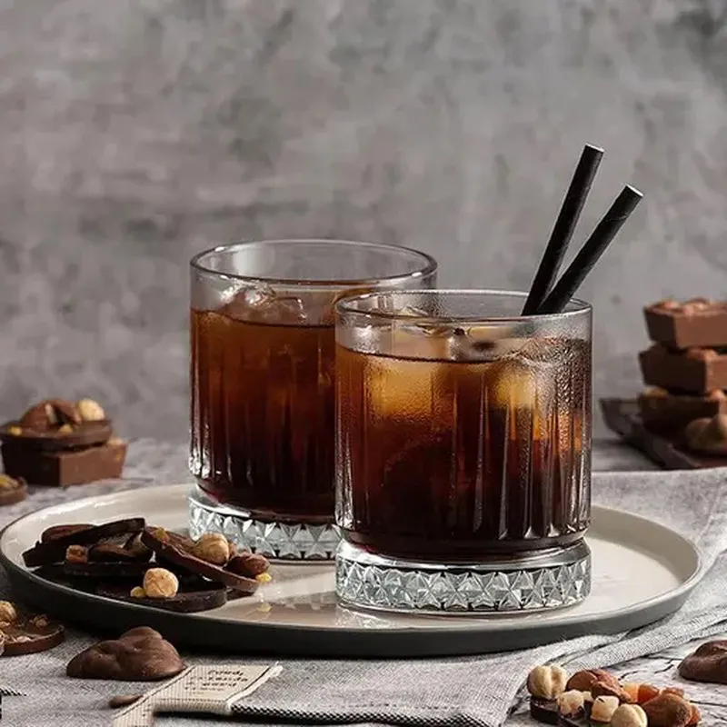 Two clear textured glasses filled with a dark beverage on a serving tray