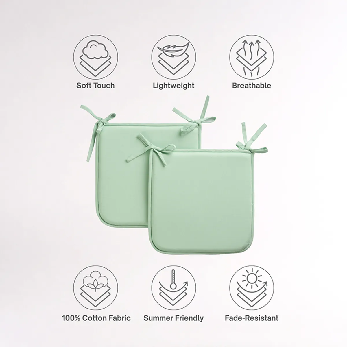 Two sage green square chair pads with tie-up corners on a plain background