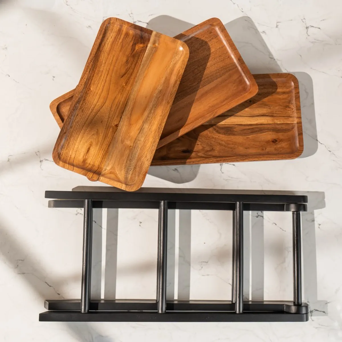 Top view of wooden trays and black stand components arranged on a marble surface
