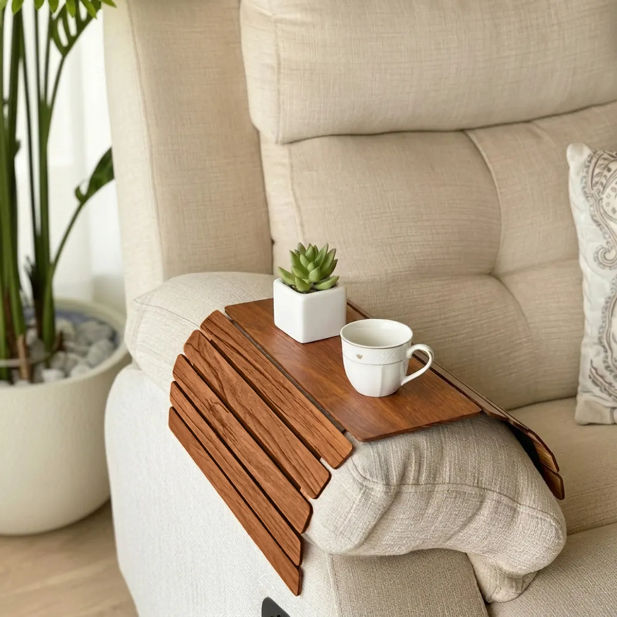 Brown sofa armrest tray holding a cup and plant on a cream recliner