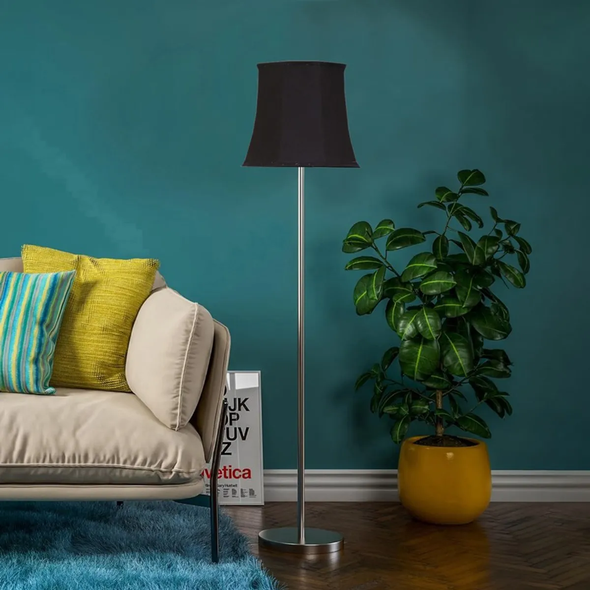 Black floor lamp with slim metal stand styled near a sofa and potted plant