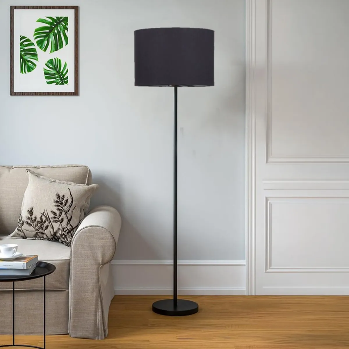 Black drum shade floor lamp in a bright living room beside a cream sofa