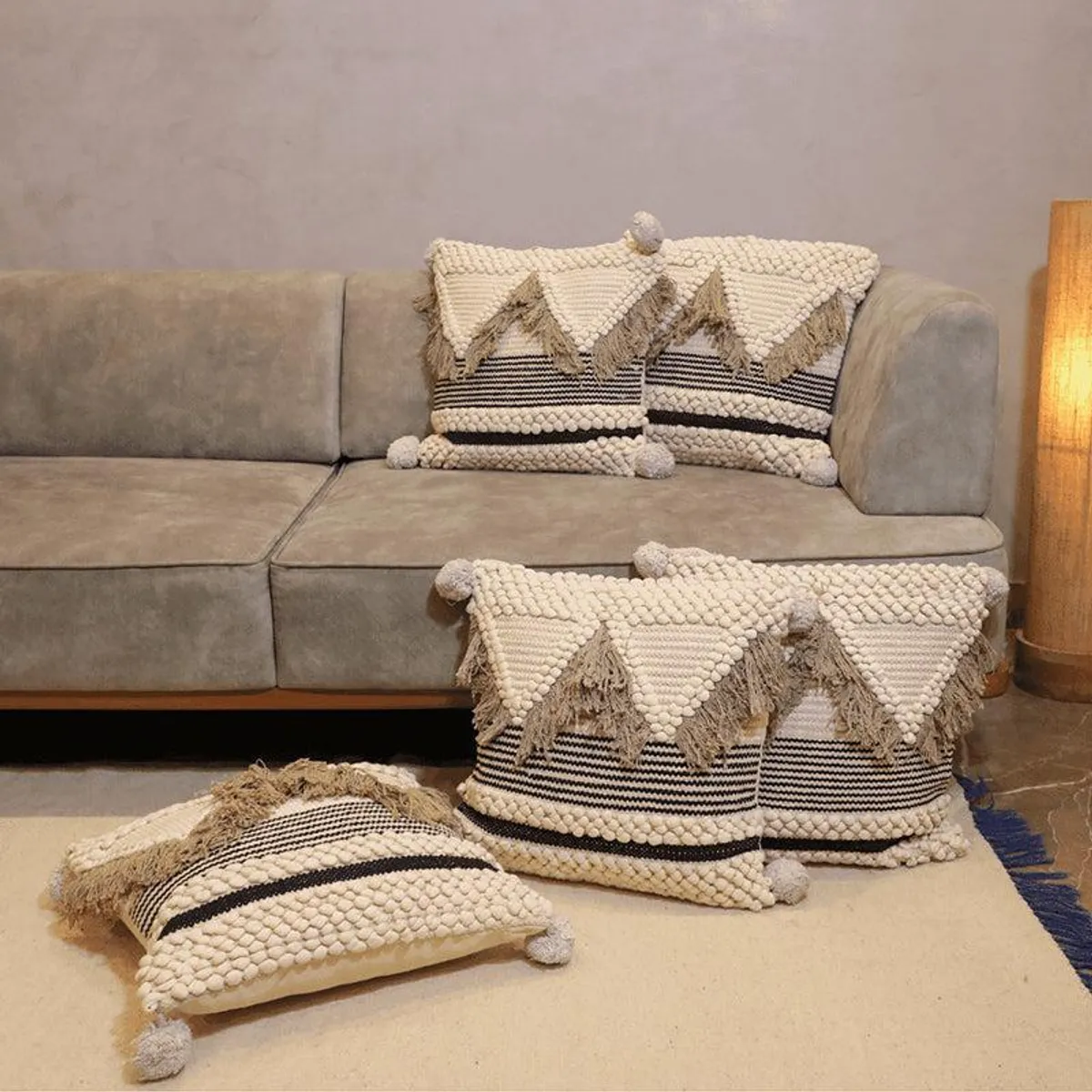 Tufted cream cushion covers with zigzag fringe and pom-poms styled on a neutral sofa