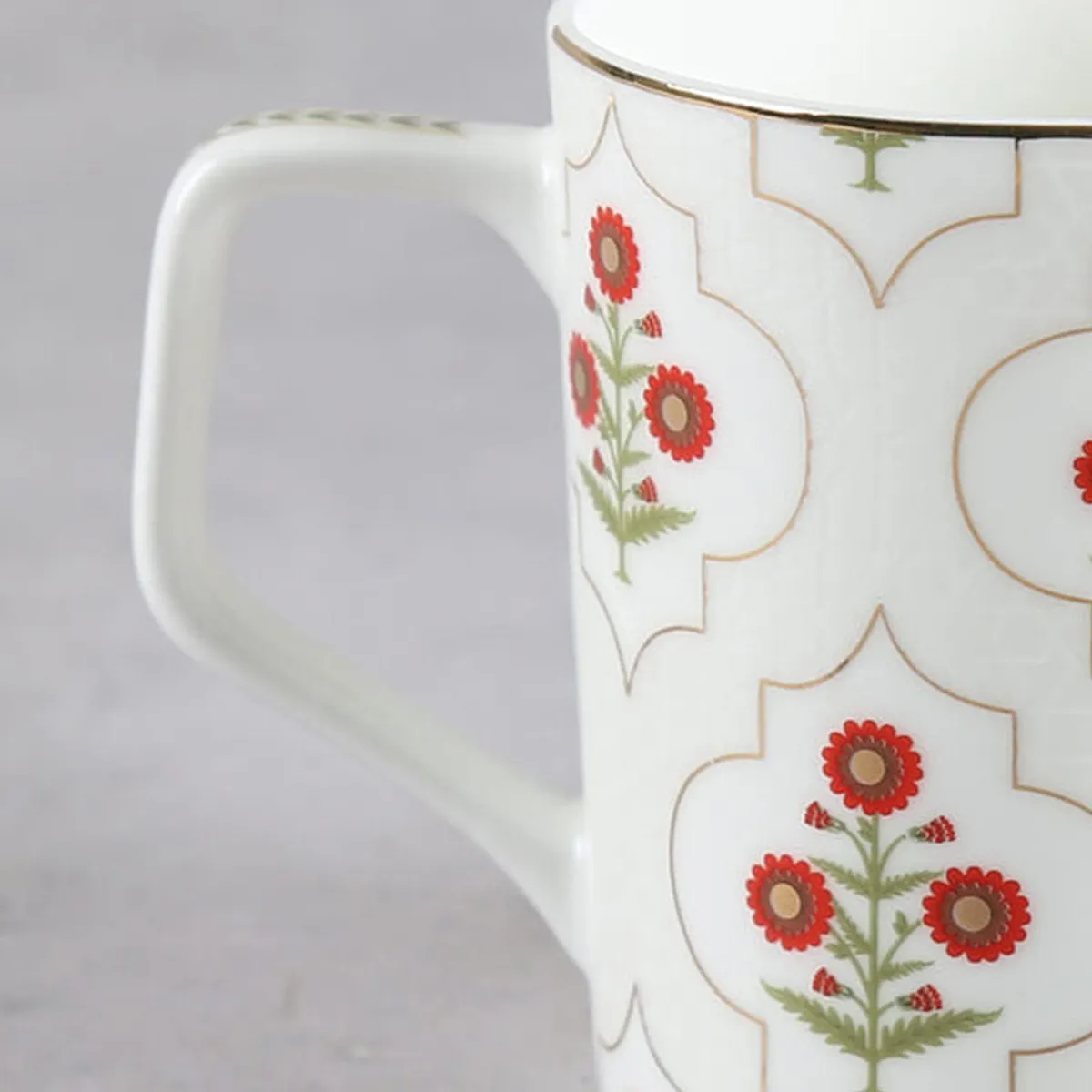 Close-up showing the white handle and red floral detailing on an ivory tea cup.