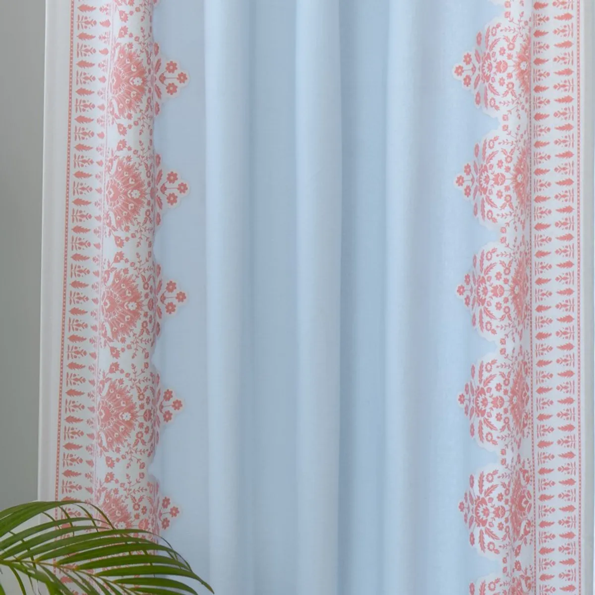 Close-up of blue curtain with detailed pink floral border