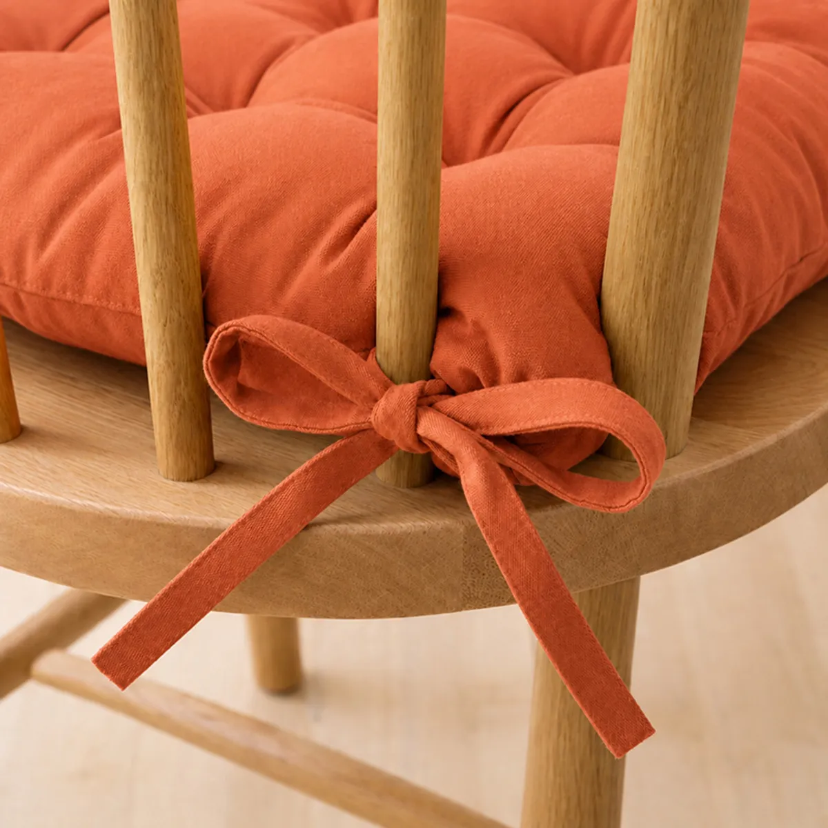 Orange chair pads placed on wooden dining chairs in a dining room setting