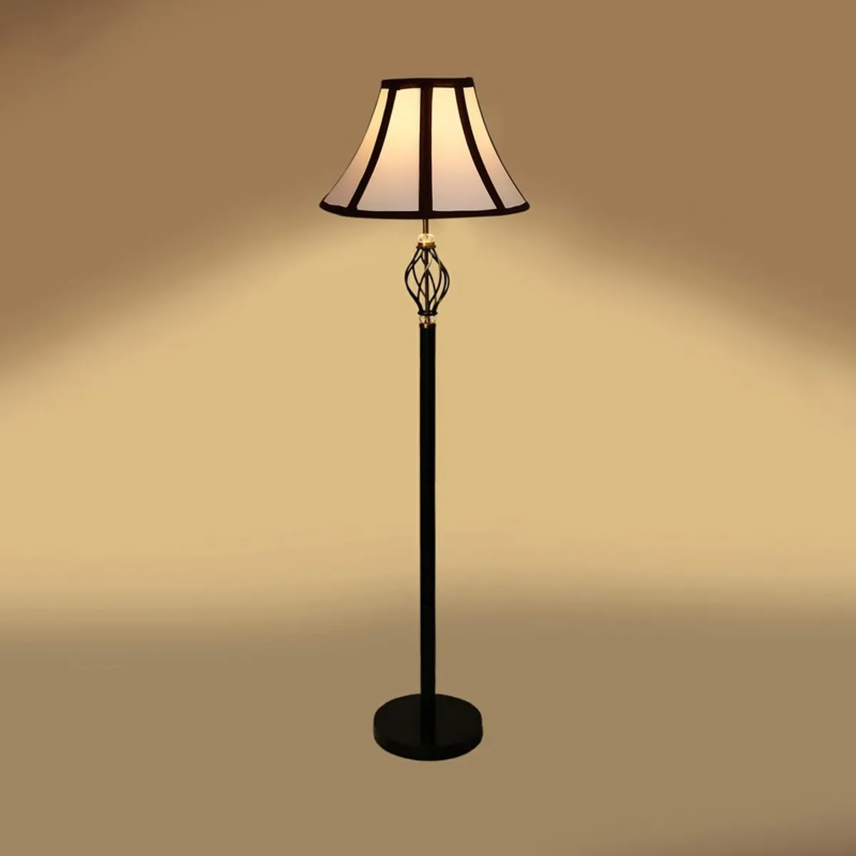 Black floor lamp with lit white paneled shade on a warm beige backdrop