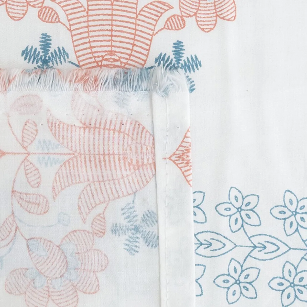 Close-up of printed bedsheet seam with blue and coral floral motifs