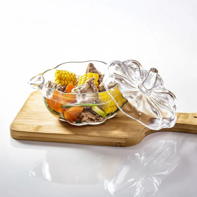 Glass snack bowl with lid placed beside it, filled with vegetables on a wooden board