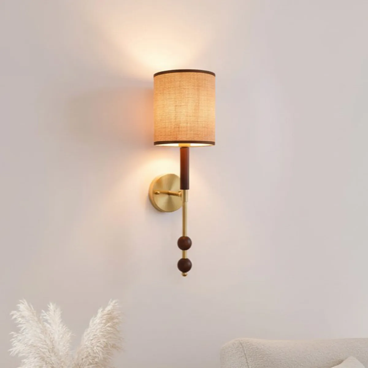 Decorative wall lamp with warm cylindrical shade against a neutral wall