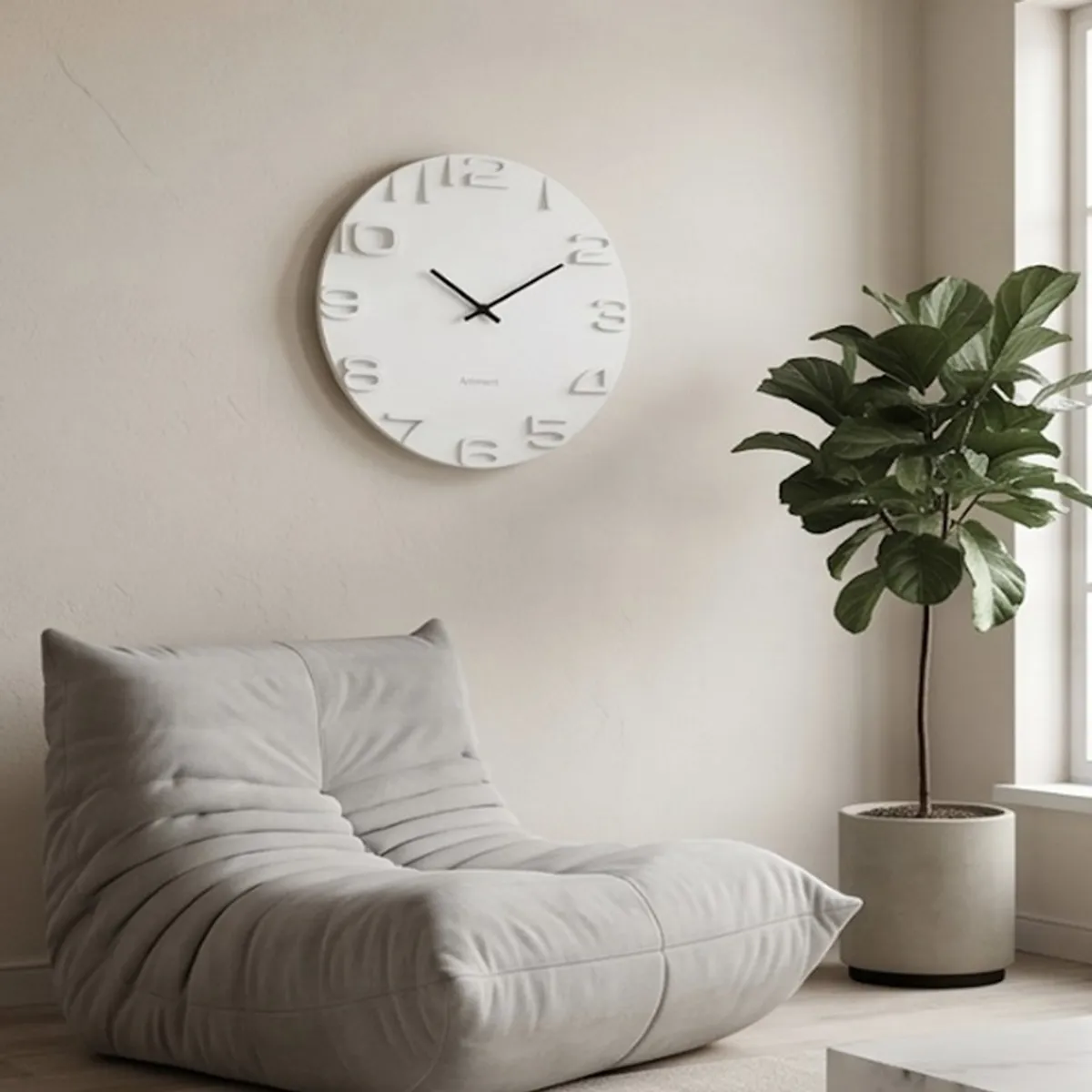 White round wall clock mounted above a lounge chair beside a potted plant