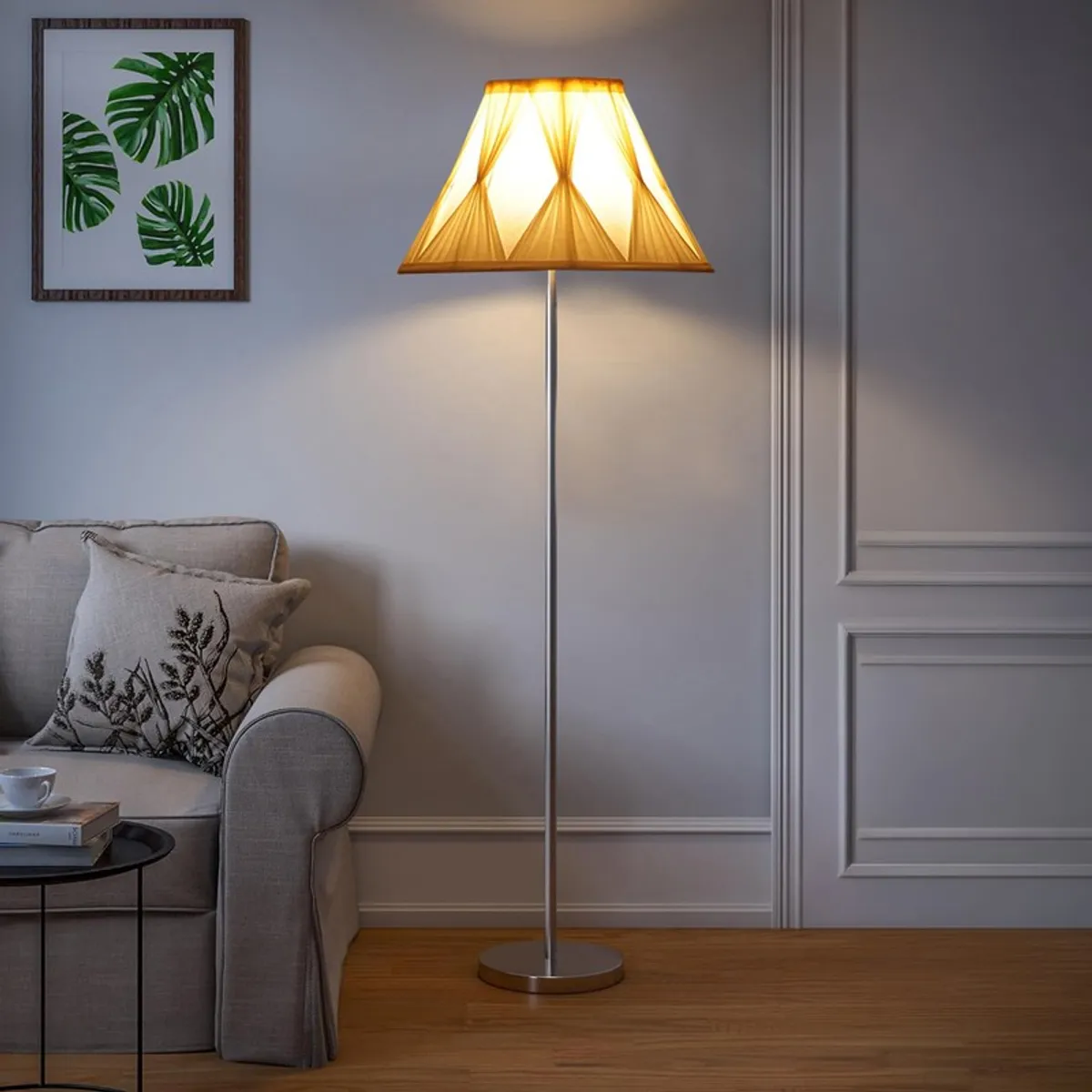 Lit cream floor lamp with pleated tapered shade in a neutral living room corner