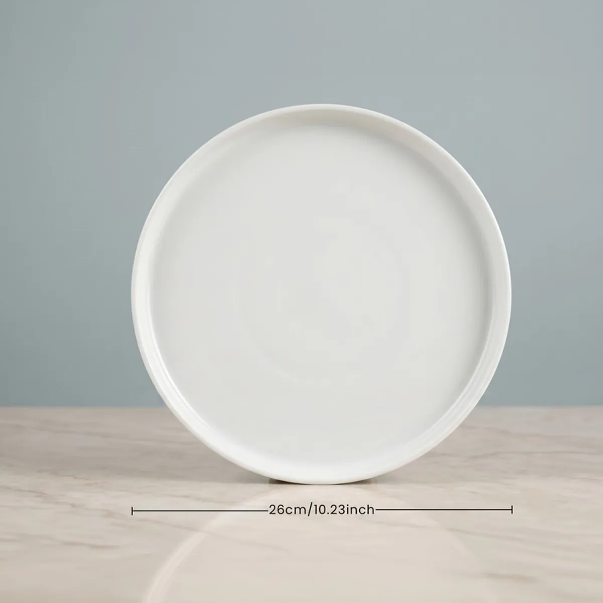 Single white round dinner plate on a tabletop against a pale blue backdrop