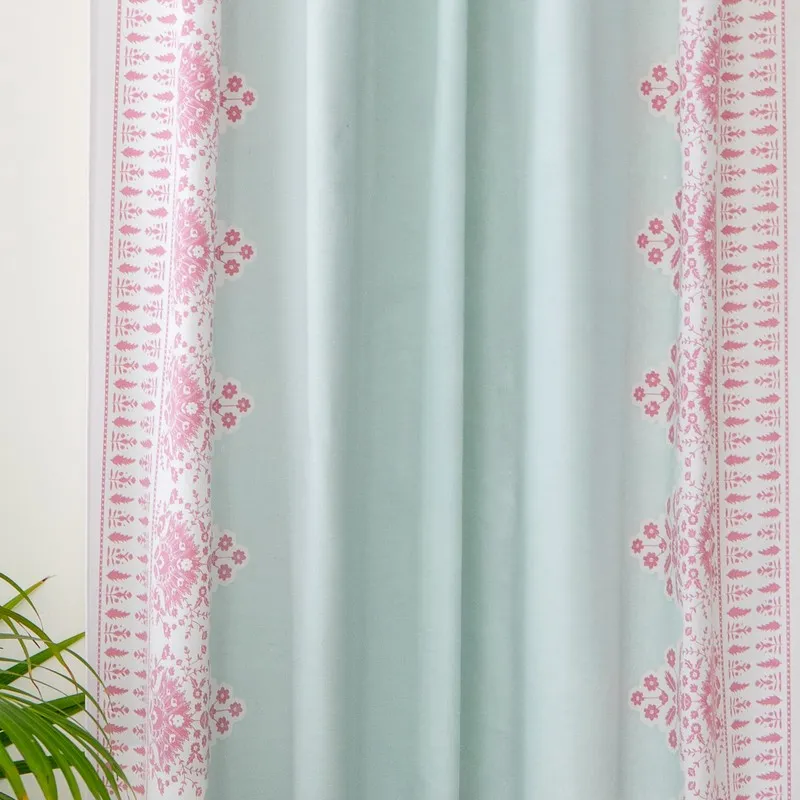 Close-up view of aqua curtain fabric with pink floral border accents