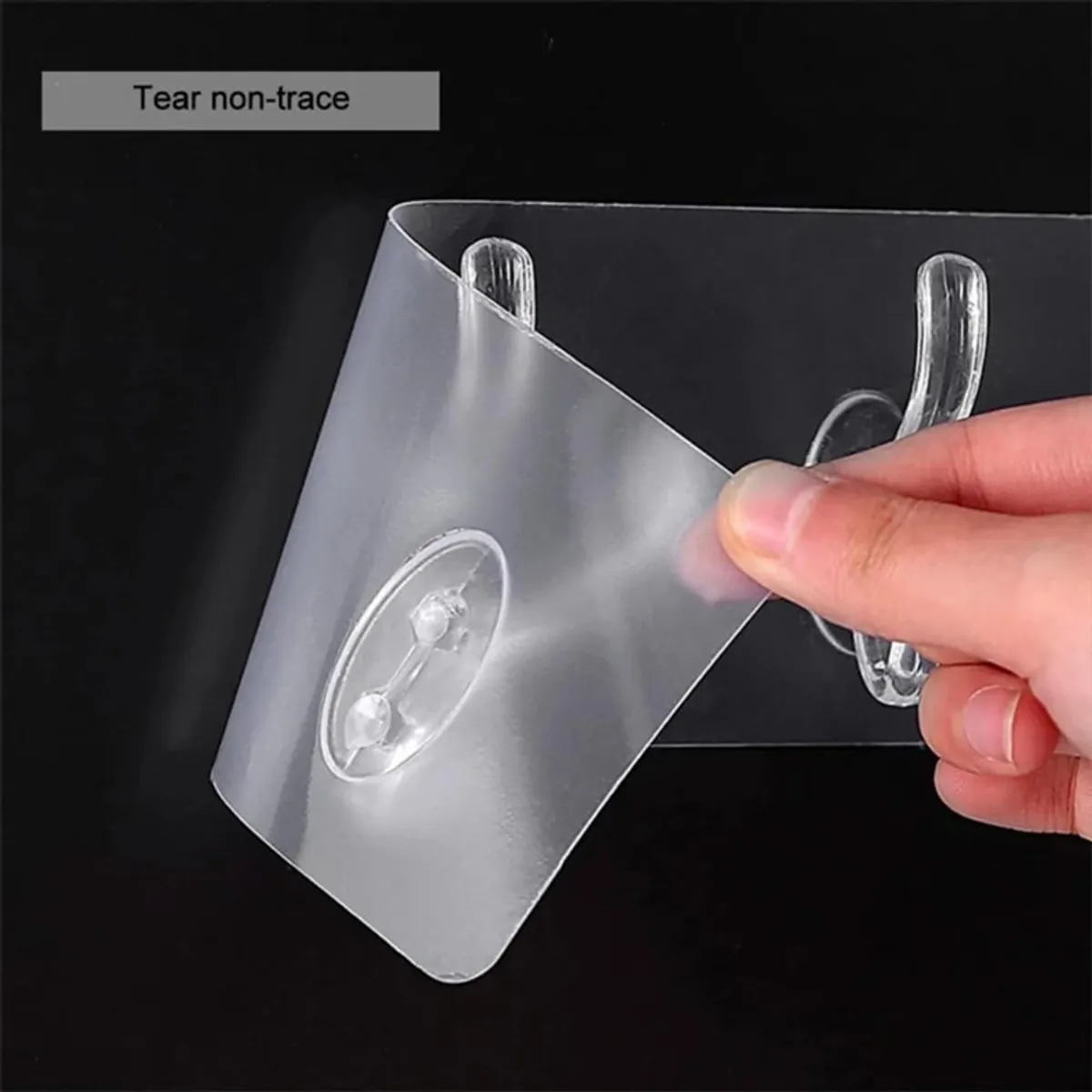Close-up of a transparent hook strip being gently peeled by hand