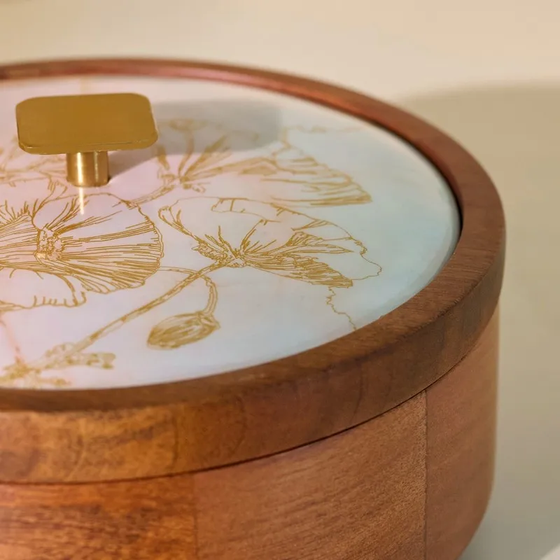 Close-up of glossy floral lid, wooden rim and gold-toned knob