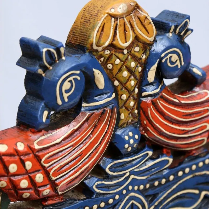 Close-up of the carved bird motif on the blue hand-painted wall accent