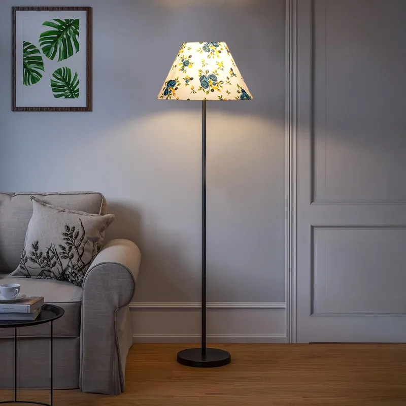 Blue floral shade floor lamp switched on beside a cream sofa