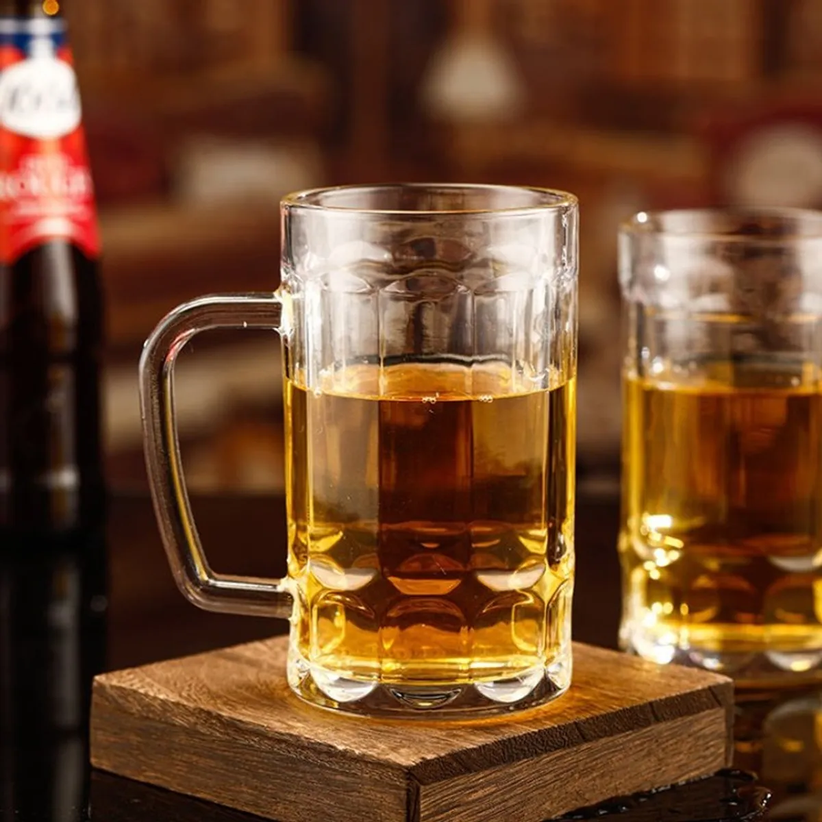 Clear beer mug filled with beer on a wooden coaster