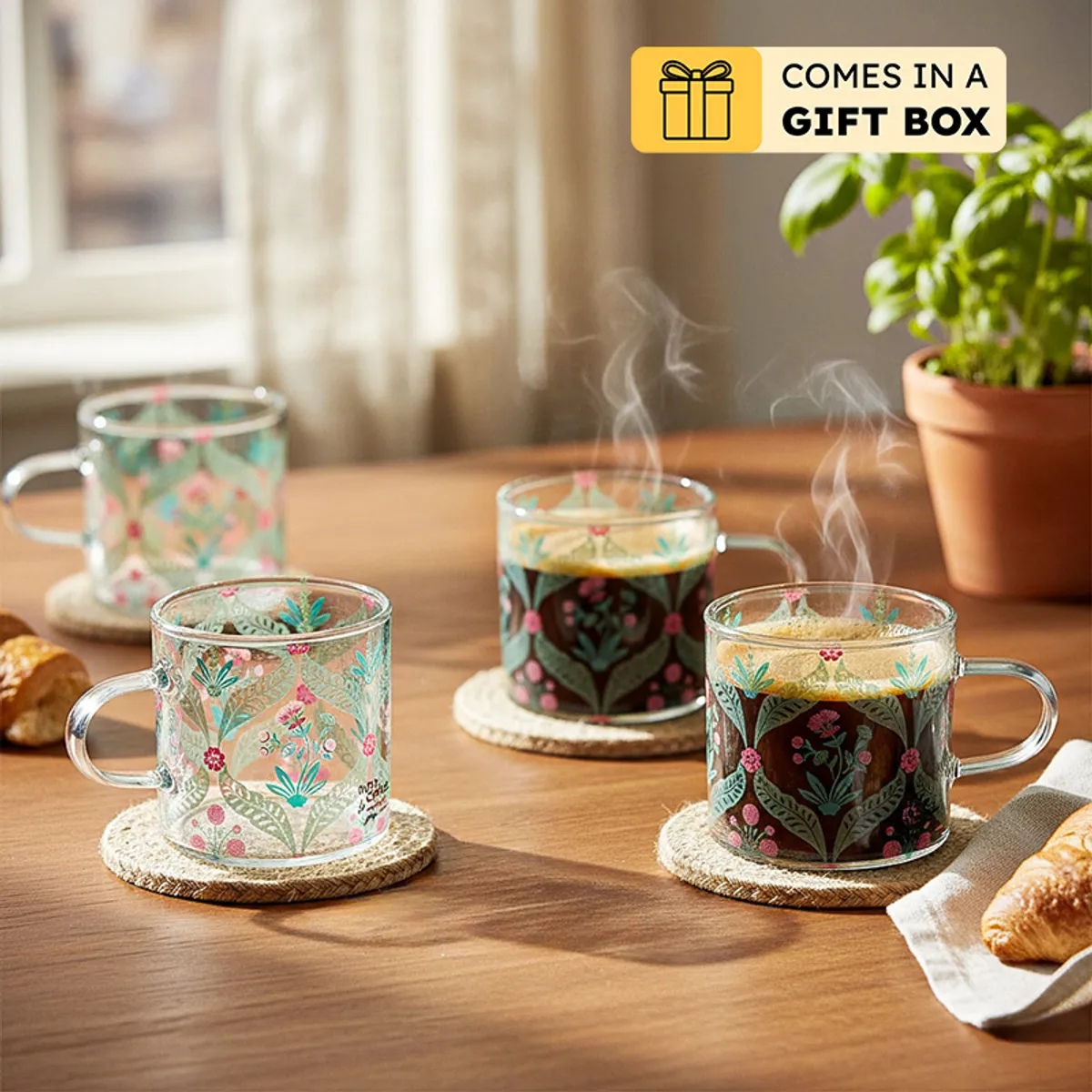 Four floral glass mugs on a table with gift box note shown