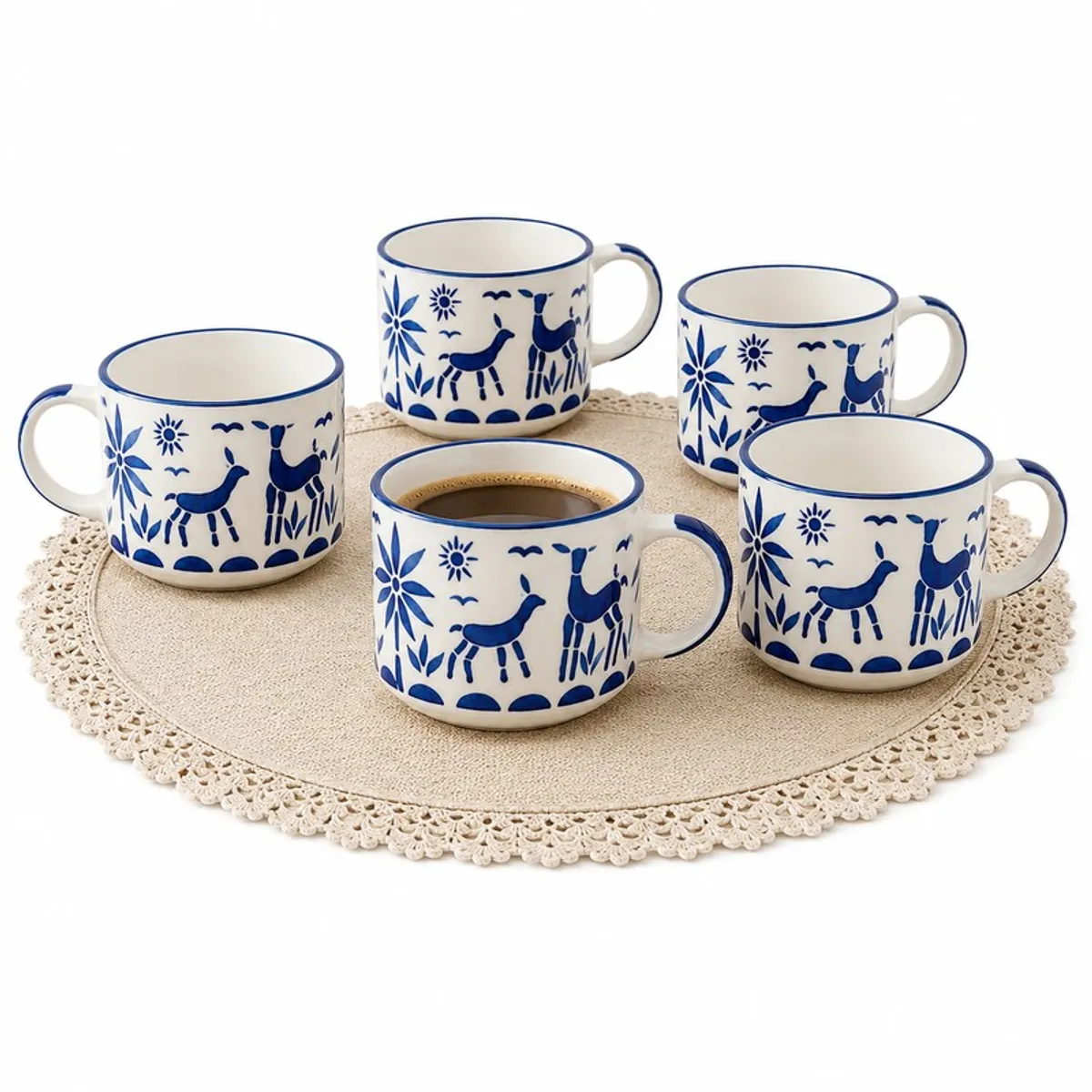 Five blue-and-white patterned ceramic cups arranged on a lace mat, one filled with tea.