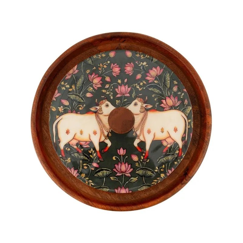 Top view of round wooden lid with floral artwork and two white cows