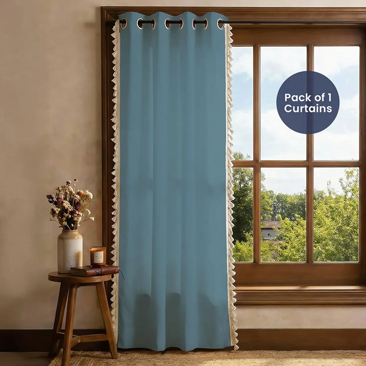 Single blue tasselled curtain covering a tall window in a warm living room